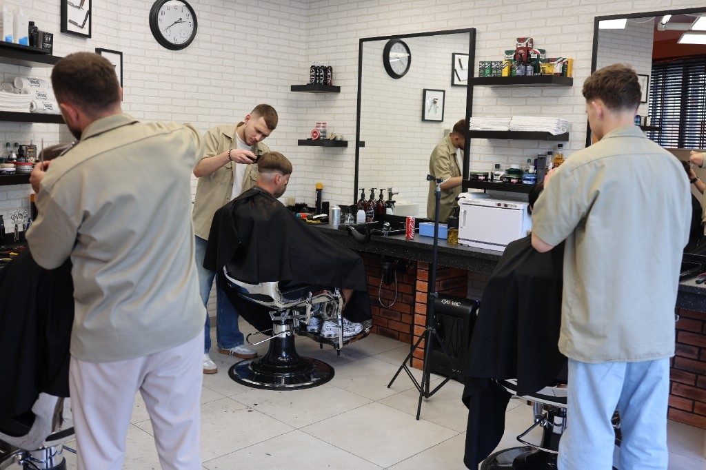 Interiér barbershopu — barbeři při práci