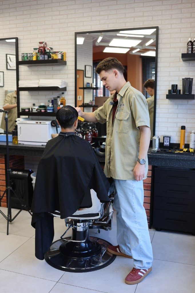 Barber při střihu u zrcadla